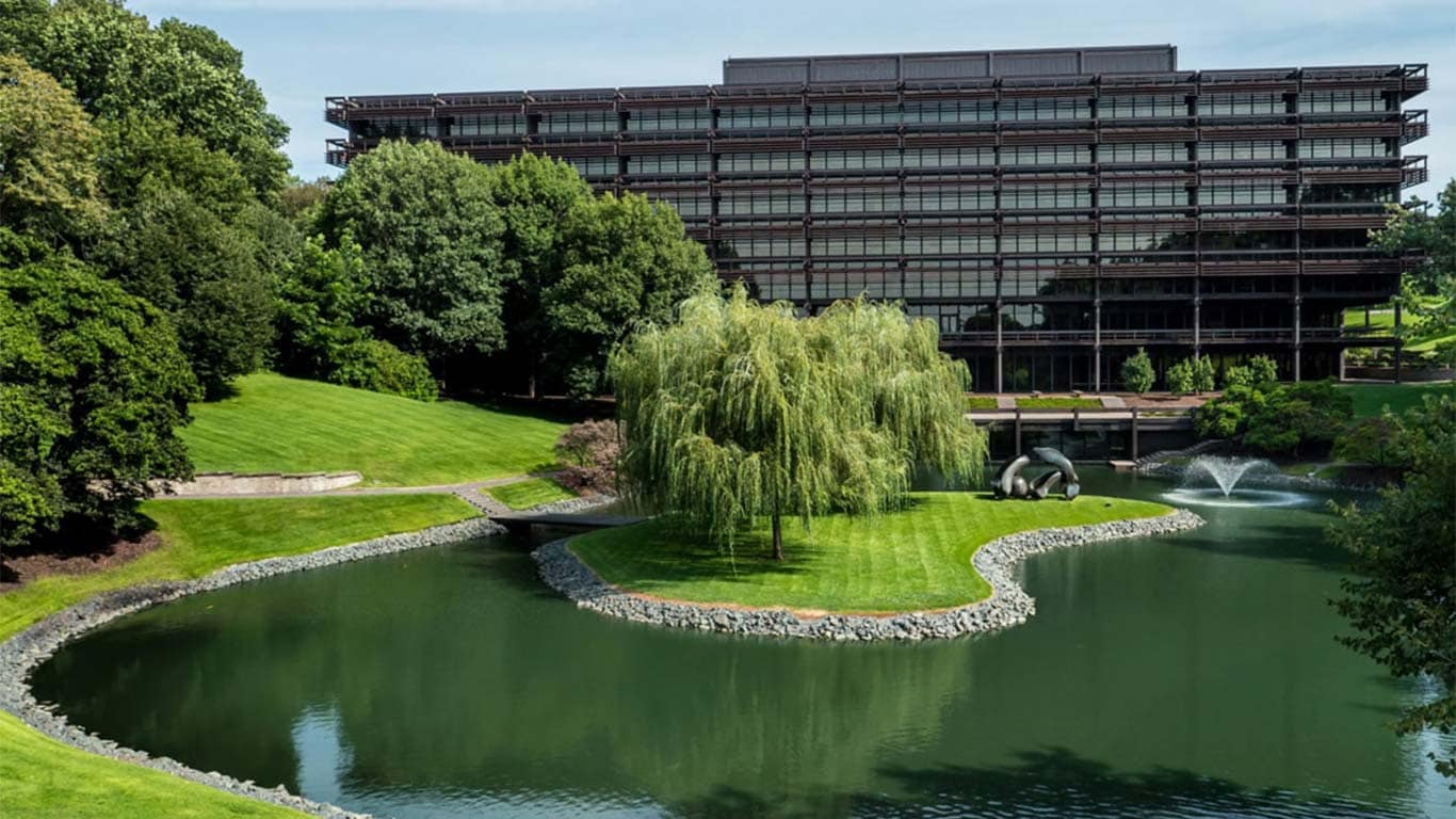 Weitläufige Frontaufnahme der John Deere Unternehmenszentrale mit einem Teich und Bäumen im Vordergrund