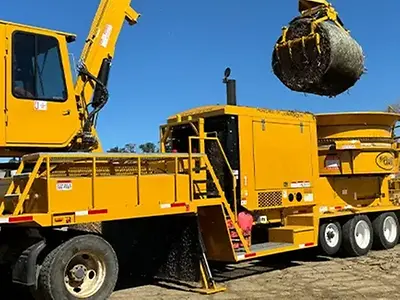 Jones Manufacturing Mighty Giant Häcksler, angetrieben von einem John Deere JD18-Motor, hebt einen Heuballen in einen Häcksler.