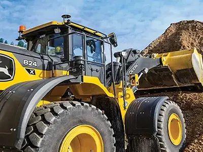 Der John Deere Radlader 824 X-Tier, angetrieben von einem John Deere JD9-Motor, entleert Erde auf einen Haufen.