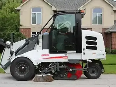 Die mechanische Elgin Sweeper Pelican Straßenkehrmaschine, angetrieben von einem John Deere 4,5-l-Industriemotor, reinigt eine Wohnstraße.