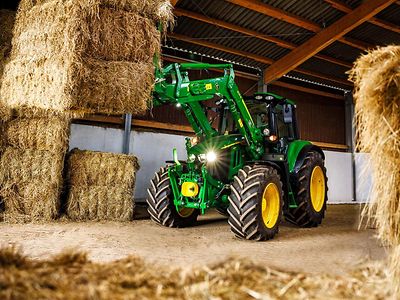 Ein Traktor in einer Scheune umgeben von ordentlich gestapelten Heuballen